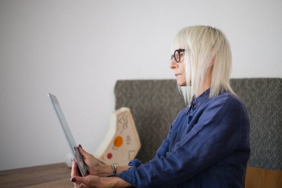 aged woman using tablet while sitting at home