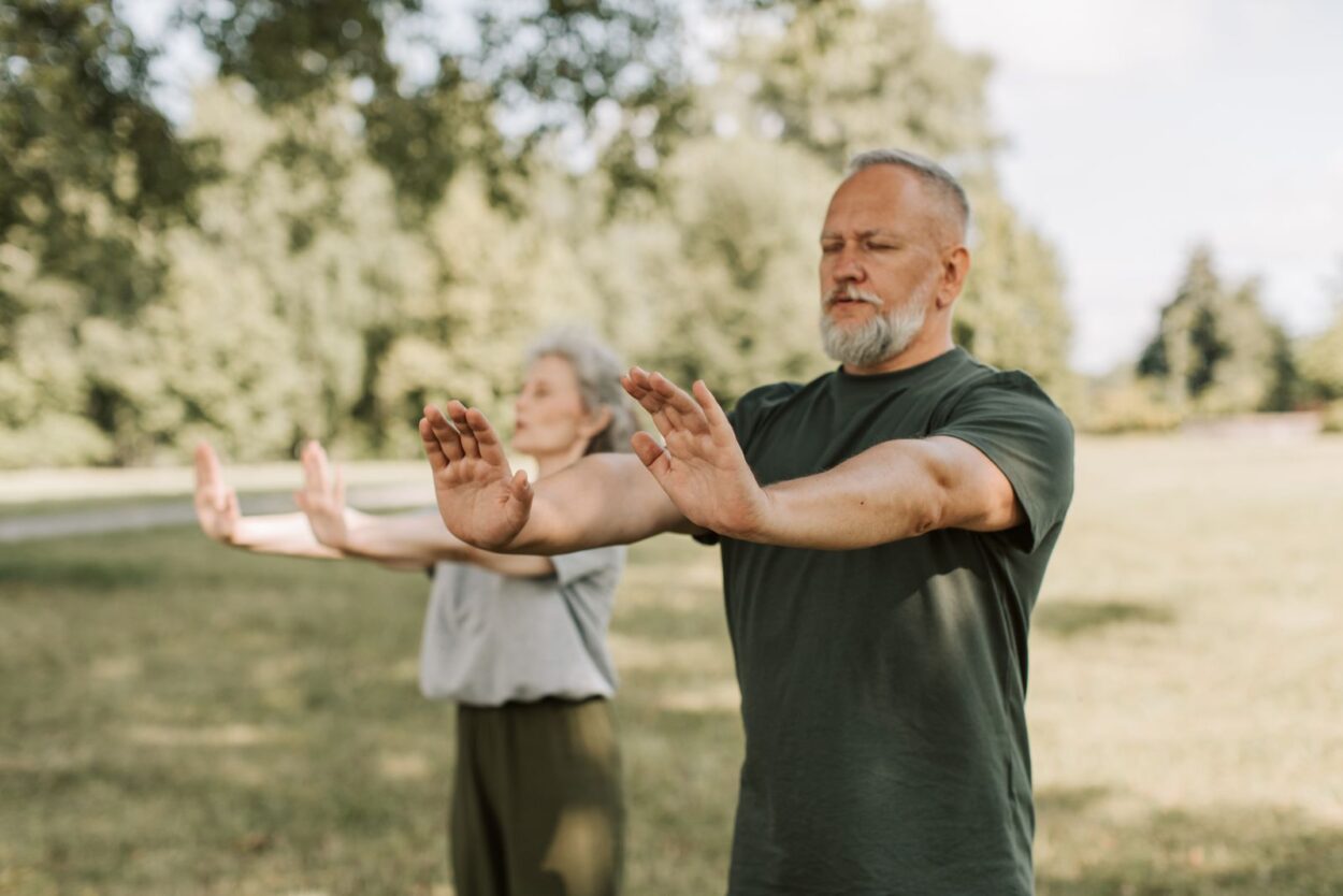 Ouder koppel doet samen buiten in het park Tai Chi-oefeningen om kracht en evenwicht te trainen
