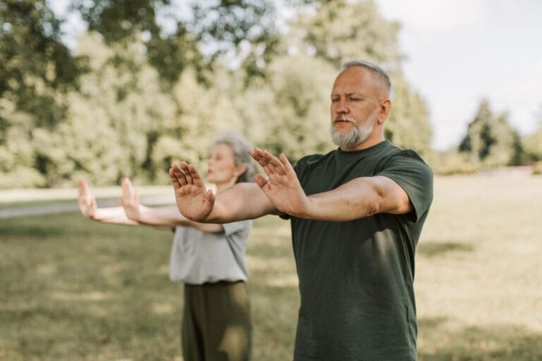 Ouder koppel doet samen buiten in het park Tai Chi-oefeningen om kracht en evenwicht te trainen